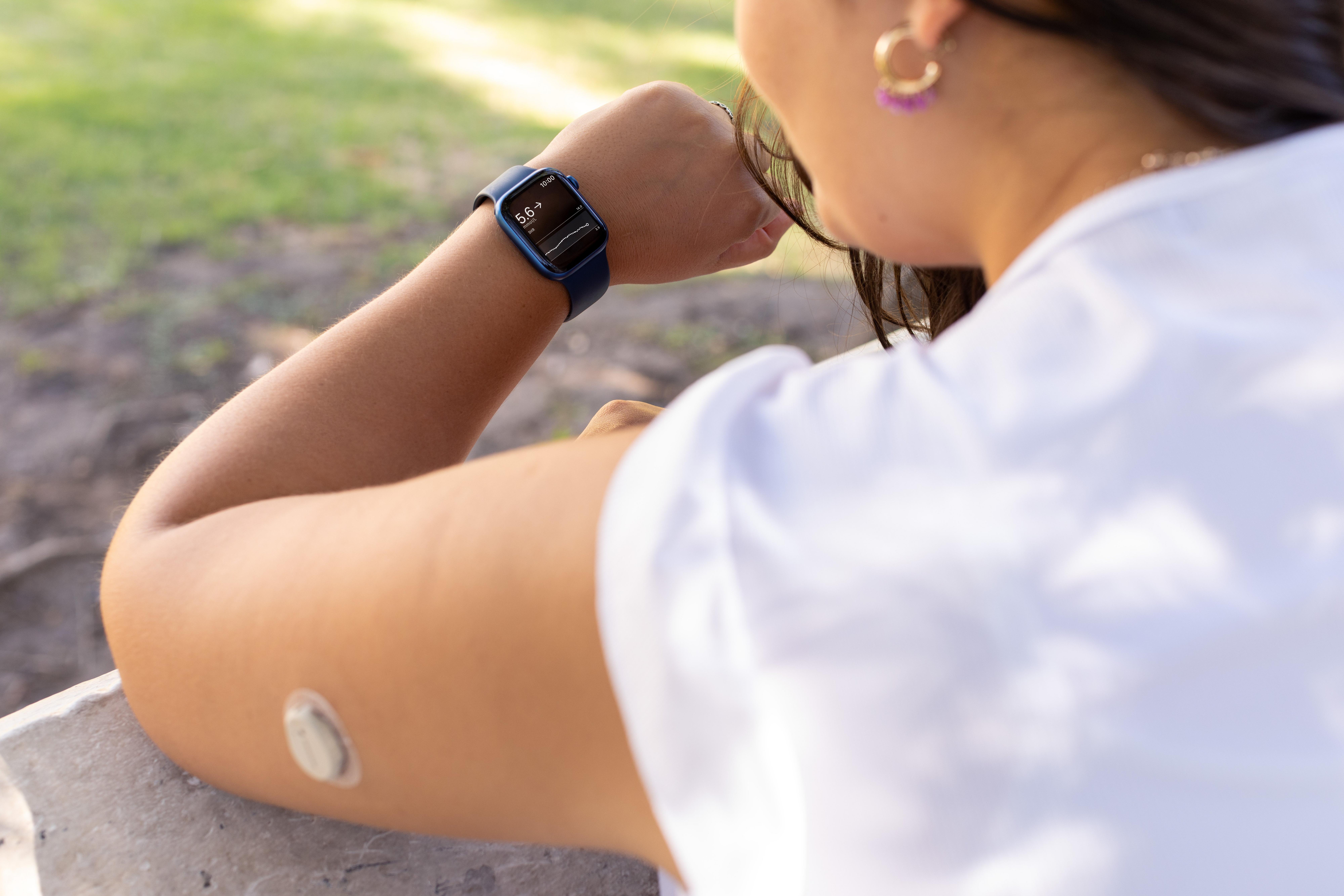 persona che guarda l'apple watch con cgm sul braccio