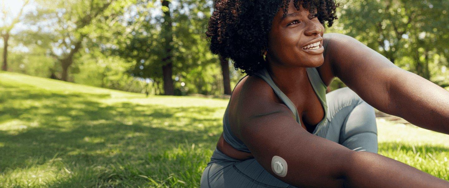 Woman smiling wearing Dexcom G7 sensor in the park