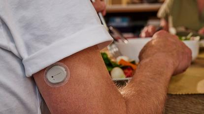 Man sitting at table with Dexcom One+ device on his arm
