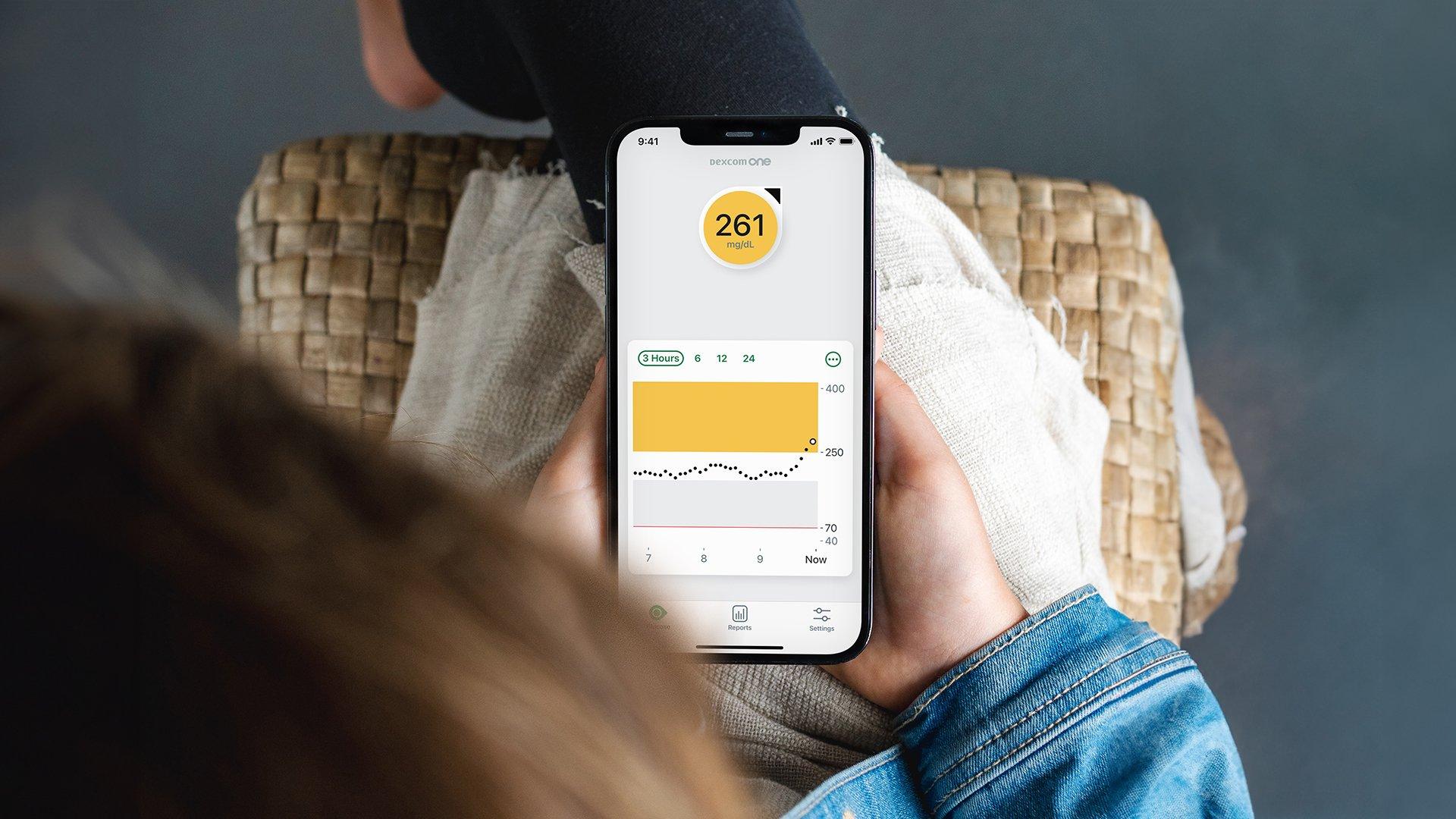 Person holding a receiver with cgm data displayed