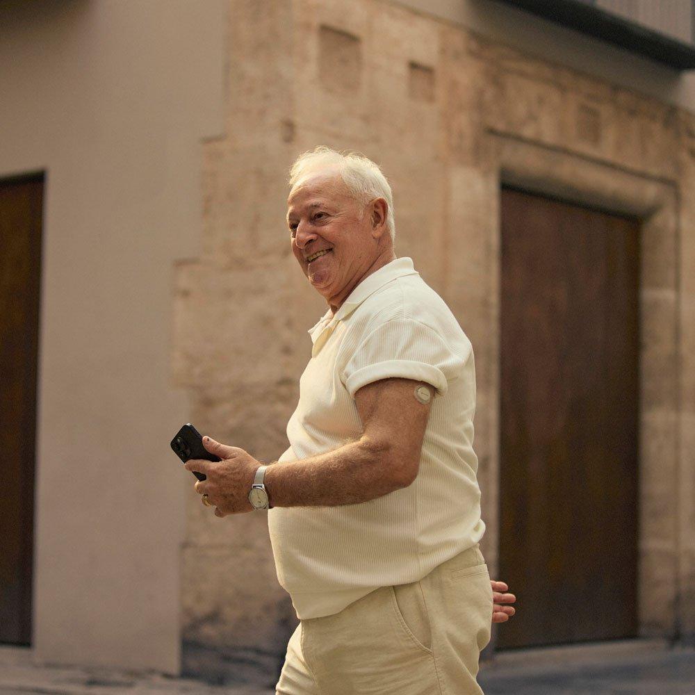 Jemand, der mit einem Dexcom Flex-Sensor am Oberarm durch die Stadt läuft