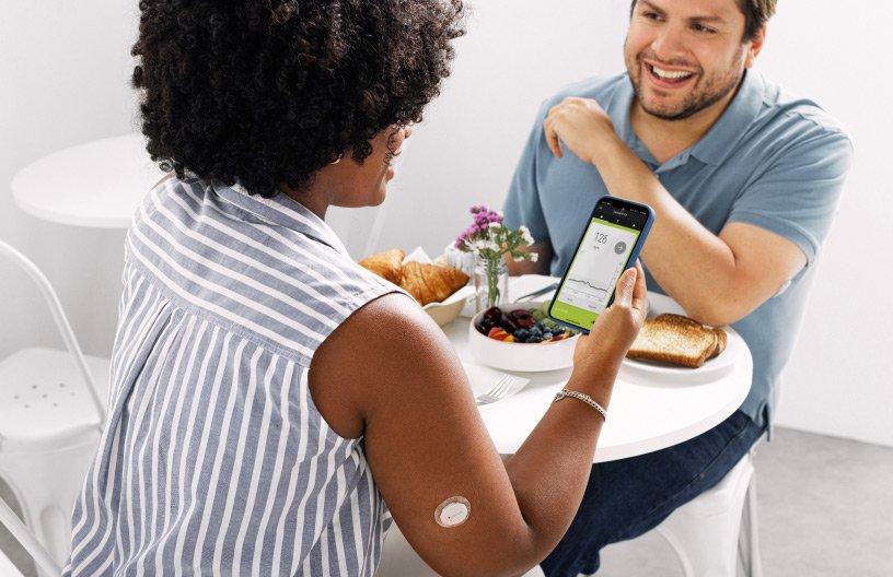 Una coppia che fa colazione e uno dei due controlla myLoop sul proprio smartphone