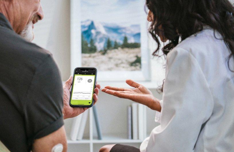 Operatore sanitario che mostra a un paziente il display myLoop su uno smartphone