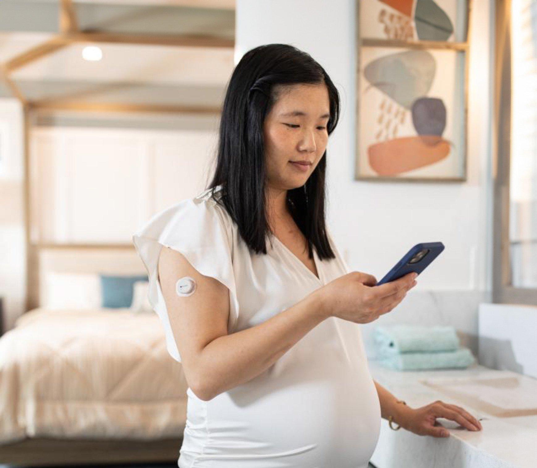 Una donna incinta che controlla il proprio smartphone