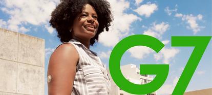 Iemand kijkt in de verte, met wolken achter zich. Ze dragen een Dexcom G7-sensor op hun arm.