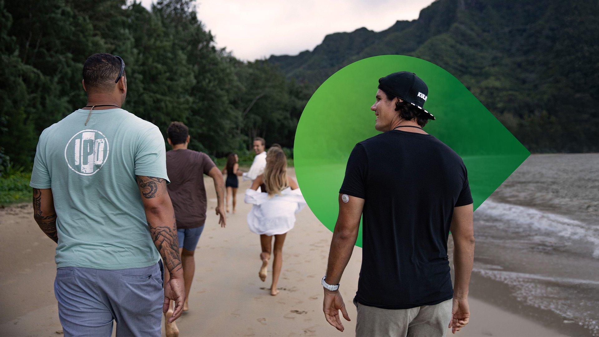 Eine Gruppe junger Leute, die mit Garmin- und Dexcom-Geräten am Strand entlanggehen.