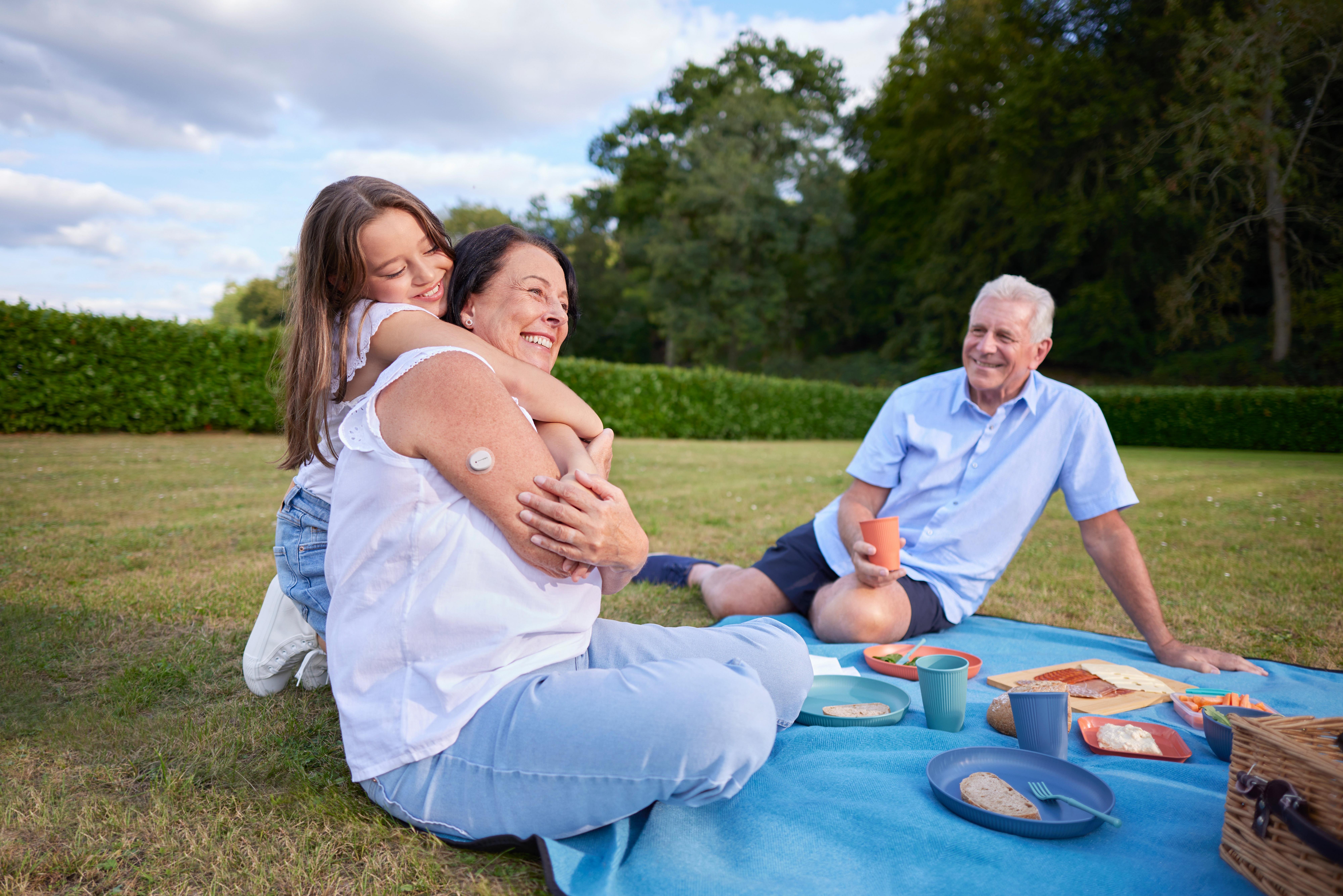 Man and girl with Dexcom device on her arm playing with balls at the beach