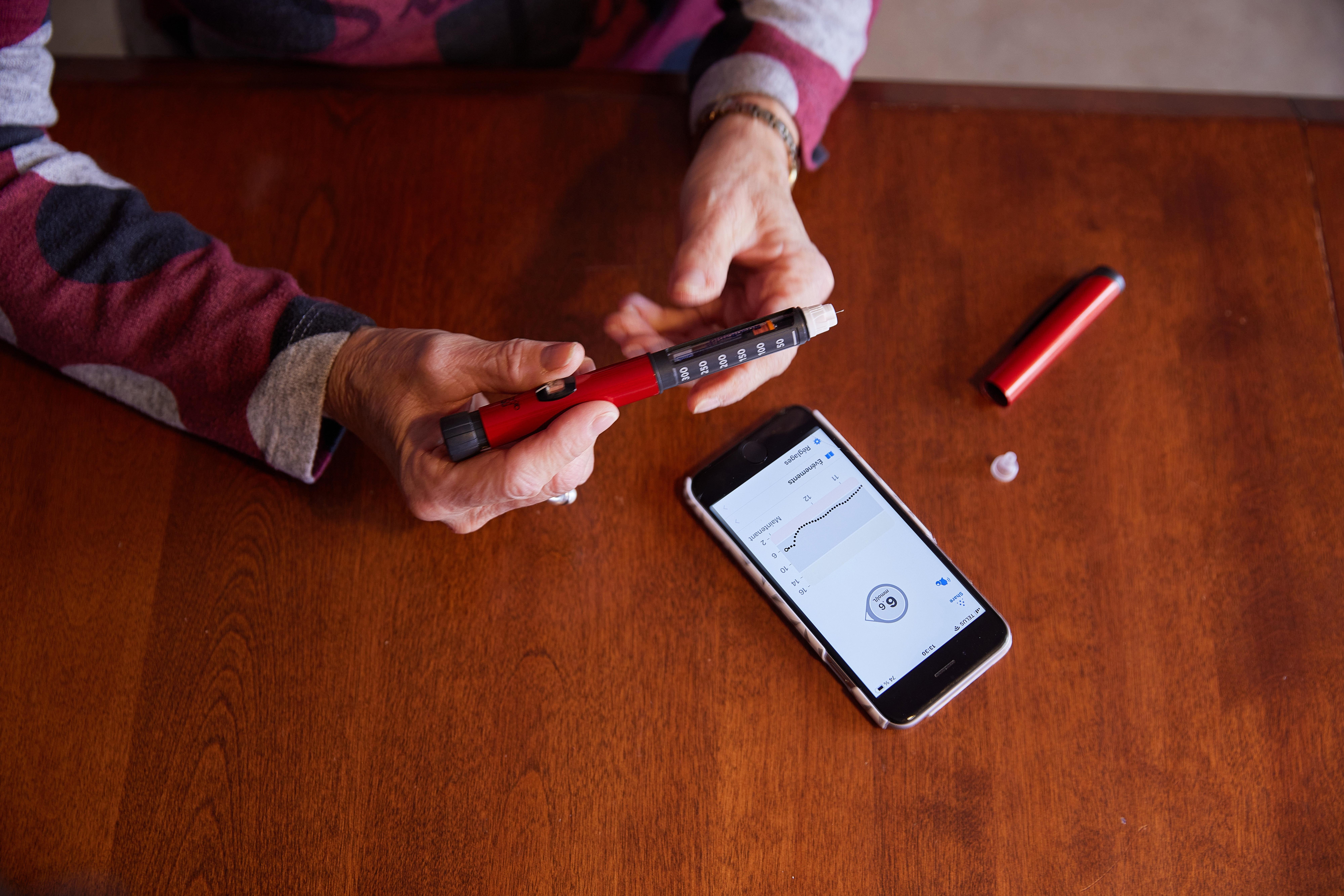 A person using insulin pen to make diabetes treatment decisions based on glucose data in the Dexcom G6 app