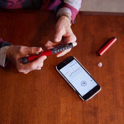 A person using insulin pen to make diabetes treatment decisions based on glucose data in the Dexcom G6 app