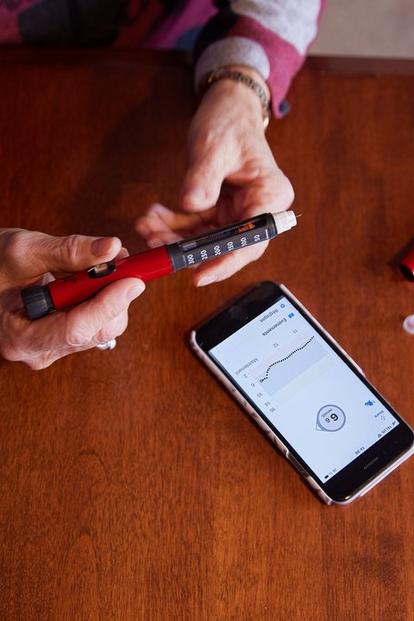A person using insulin pen to make diabetes treatment decisions based on glucose data in the Dexcom G6 app