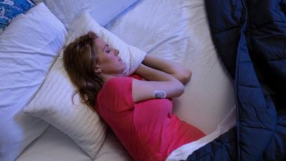 Moteris miega dėvėdama "Dexcom" jutiklį
