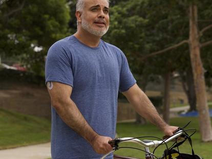 Man holding bicycle handles in a park