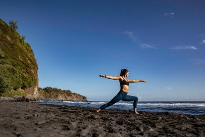 Person on a beach doing yoga with garmin watch on arm