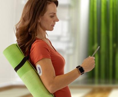 Schwangere Frau mit Dexcom G6 Gerät schaut auf ein Telefon
