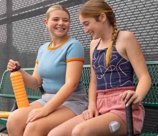 two girls on a tenis field bench using an HCL system