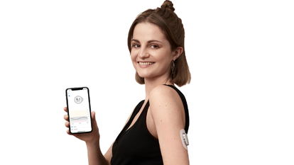A woman holding her smart device displaying real-time glucose readings
