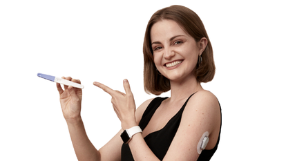 young woman with diabetes wearing a Dexcom CGM sensor holds up a phone which has the Dexcom app displayed