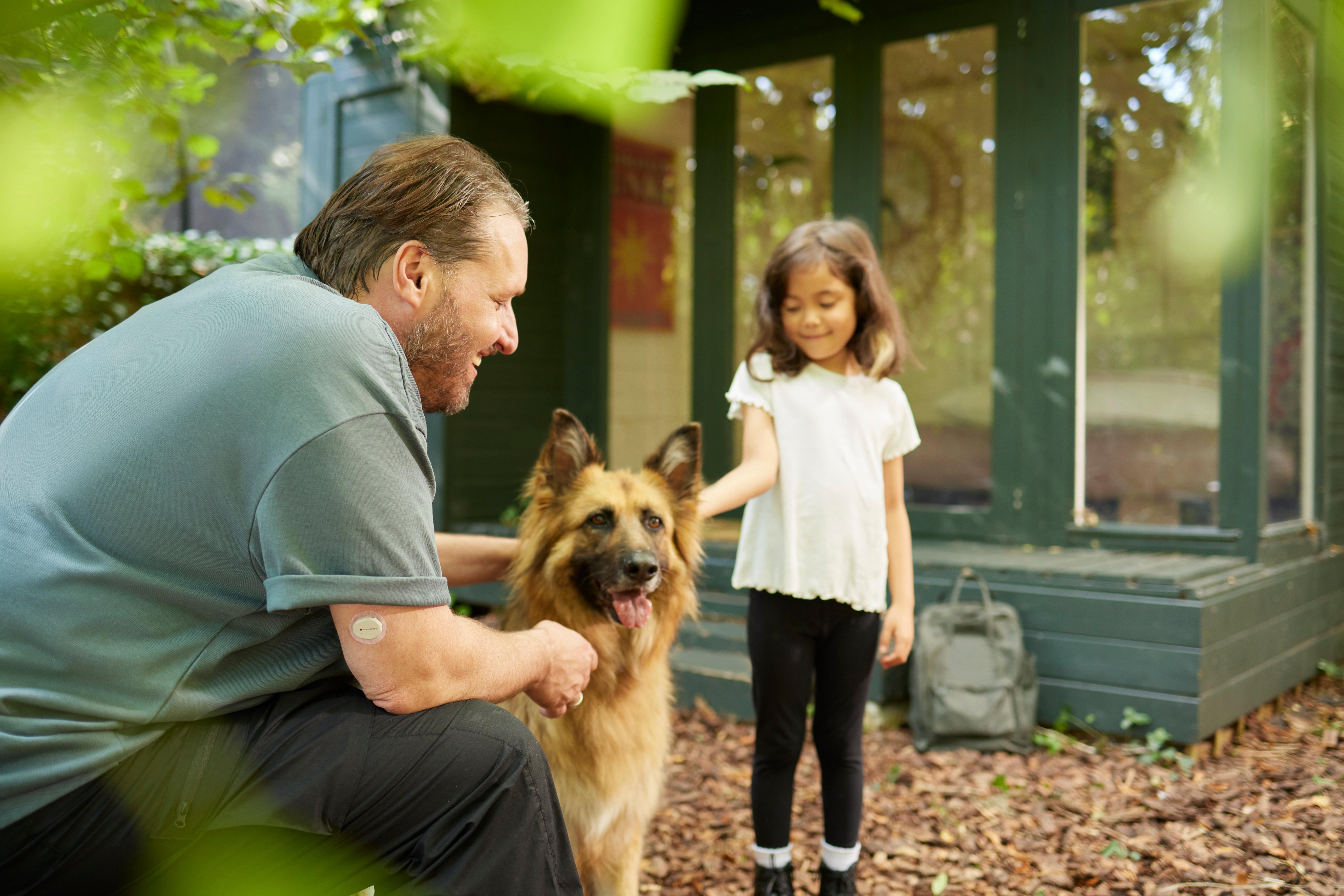 Man wearing dexcom ONE+ sensor with dog and daughter