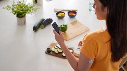 A lady prepping food while wearing a Dexcom ONE+ device