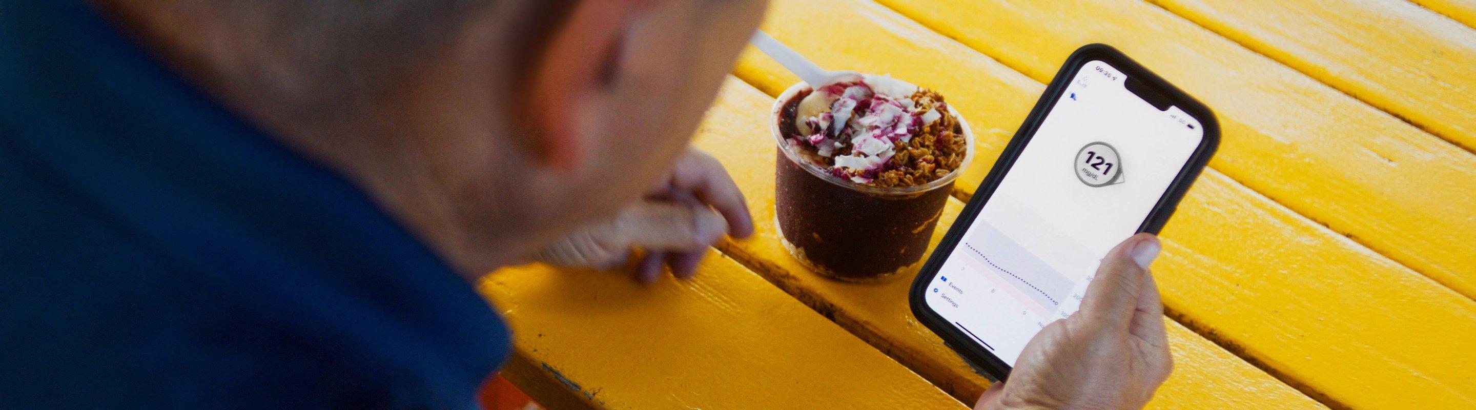 Man checking his glucose levels next to a yogurt parfait