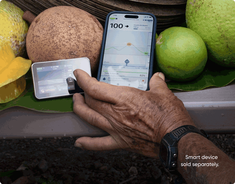 Man Showing Phone and Product on a Table of Fruit
