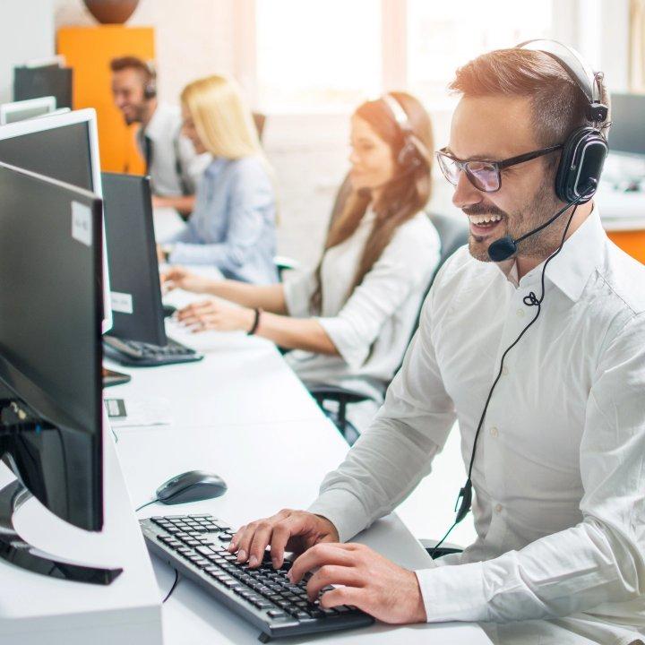 man smiling typing on a work computer