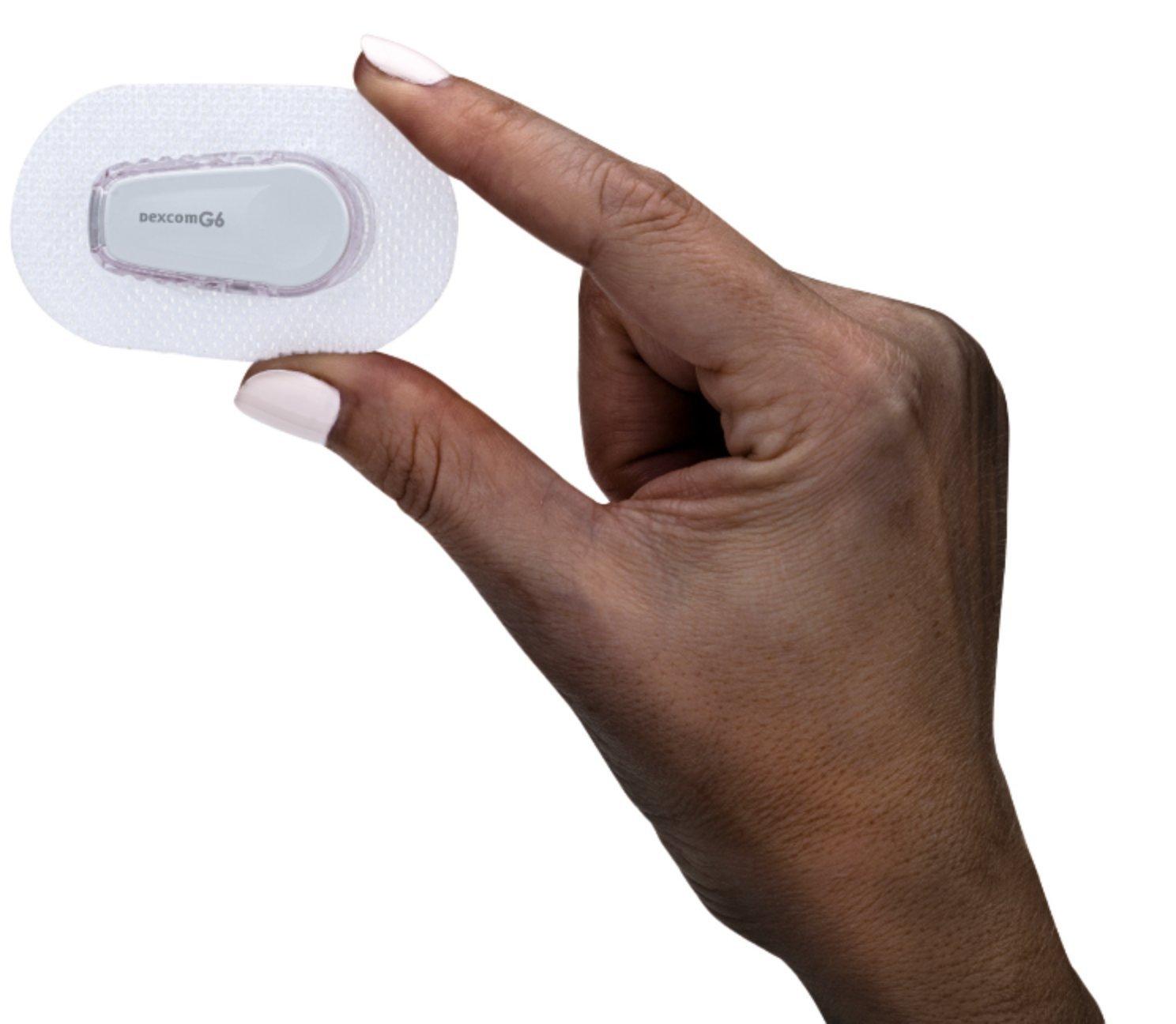 hand holding up the G6 sensor/transmitter with overpatch