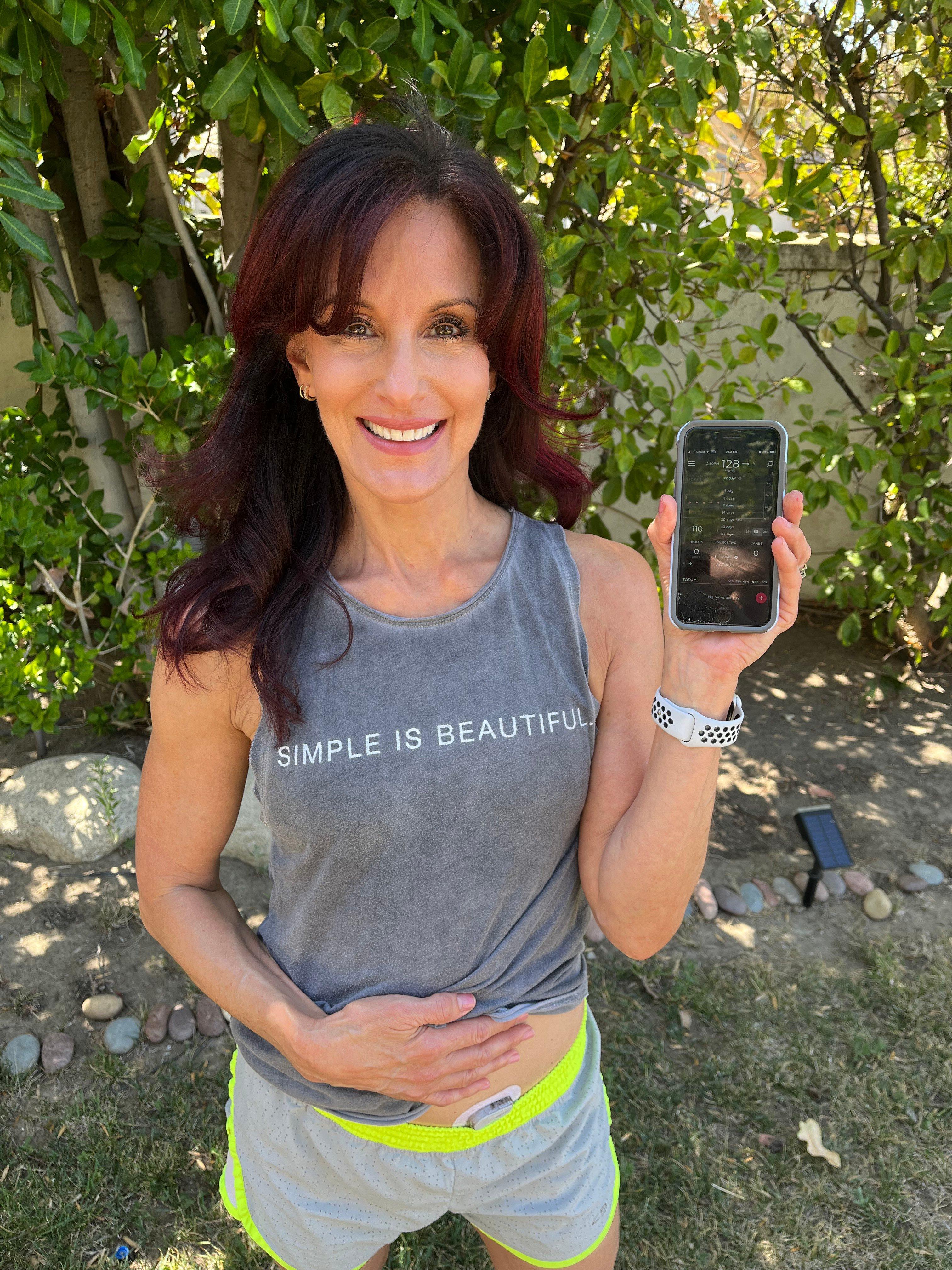 woman smiling holding phone with dexcom app
