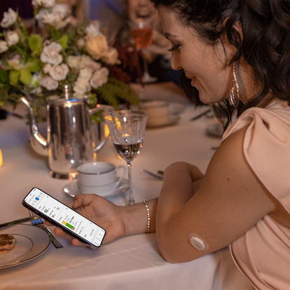 Woman at restaurant looking at the Dexcom G7 Clarity app data