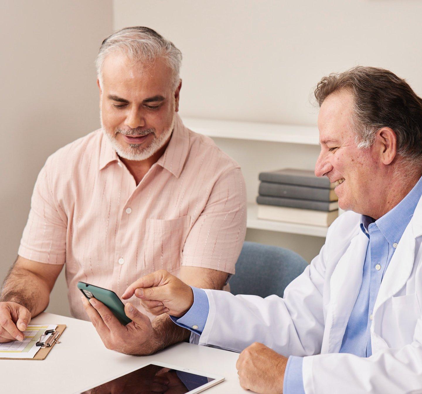 Image of doctor and patient looking at a smartphone with the Dexcom G7 app