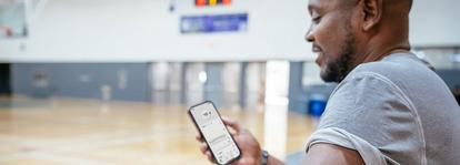 man looking at dexcom app on basketball court