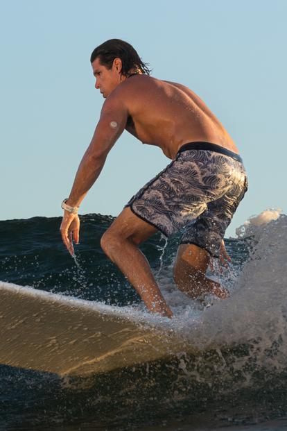 man riding surfboard in wave wearing dexcom g7 sensor