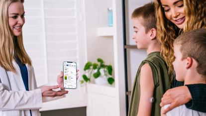 female doctor showing dexcom clarity app screen to mother and two sons