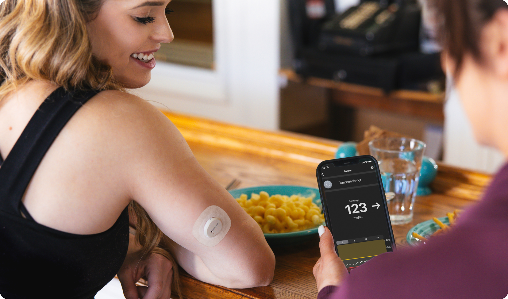 woman wearing dexcom and person checking app