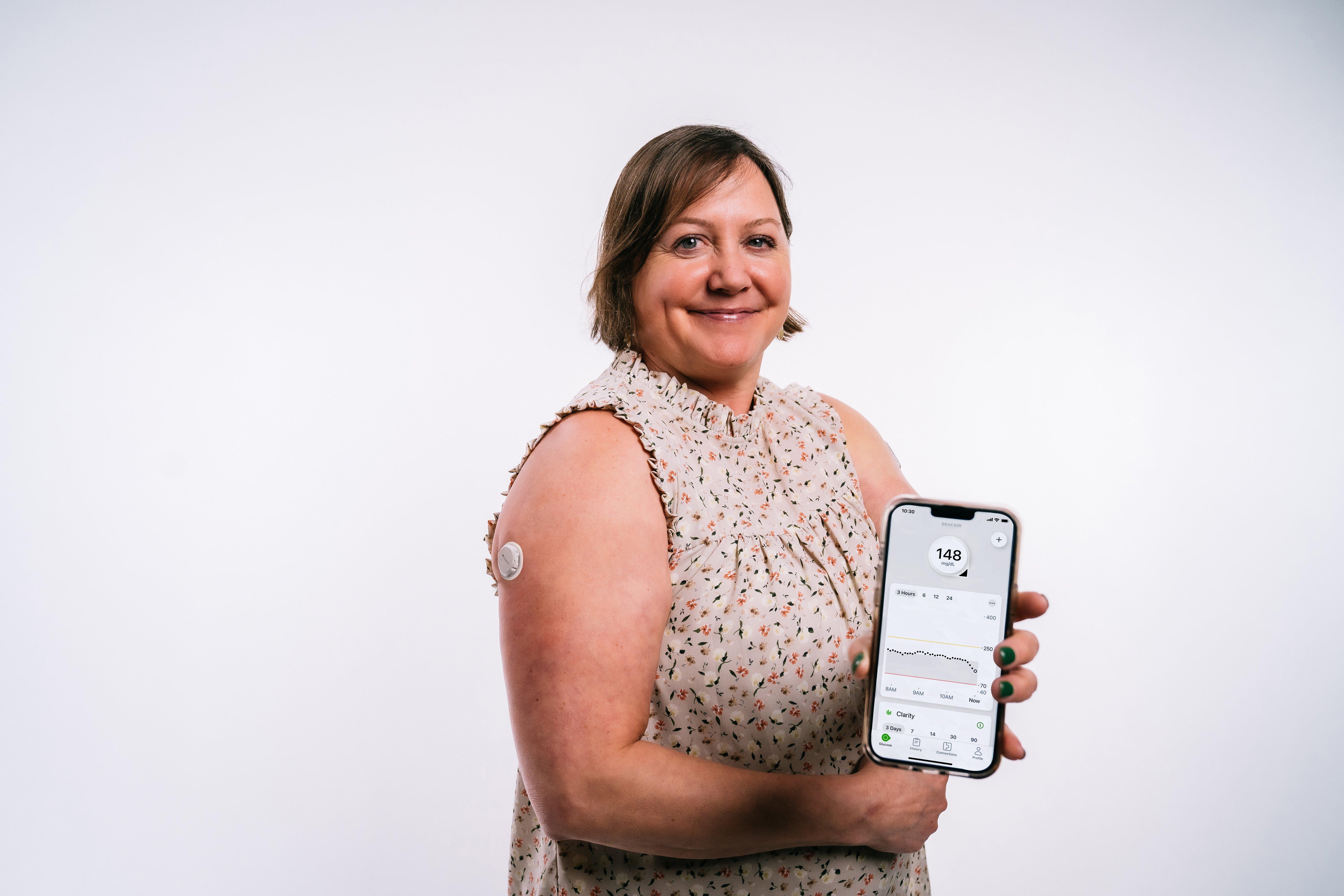 image of woman holding smartphone with dexcom app screen