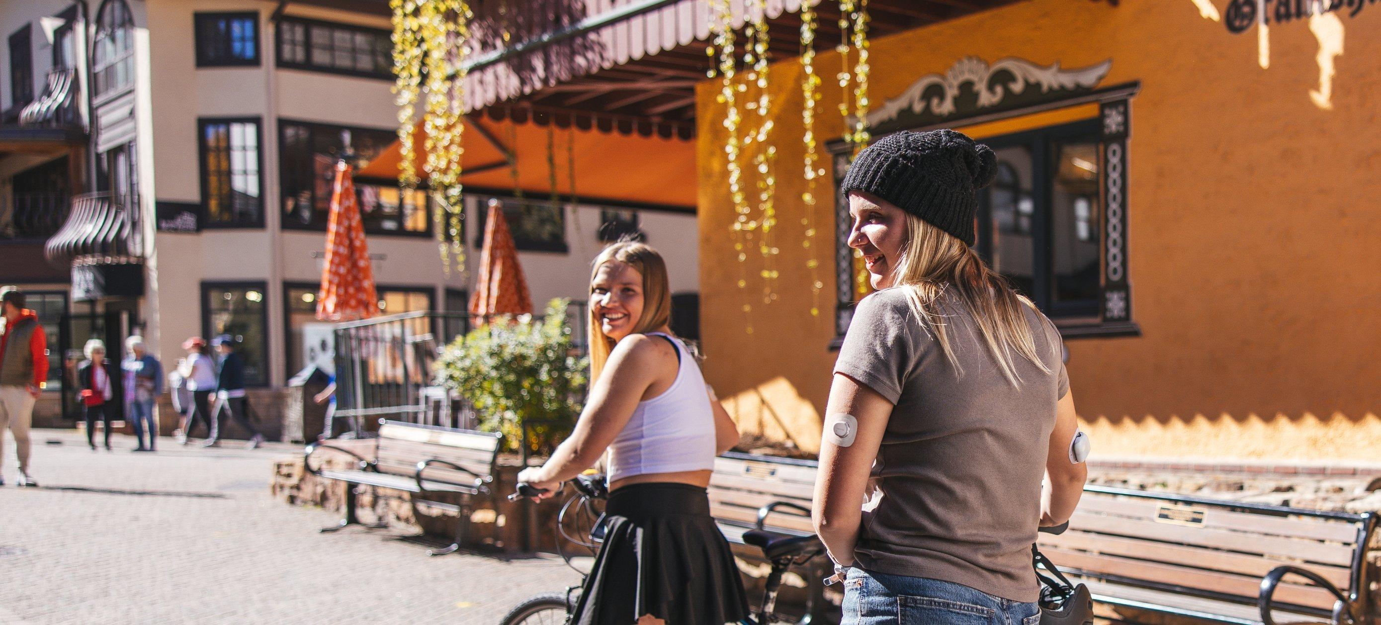 Girl walking bike smiling wearing Dexcom G7 and Omnipod 5