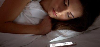 Woman sleeping next to Dexcom app in phone