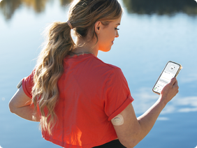 Woman with Dexcom G7 and Omnipod 5 looking at app on phone