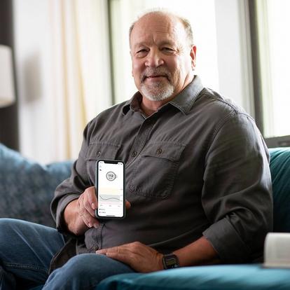 Man on couch holding smartphone with glucose levels