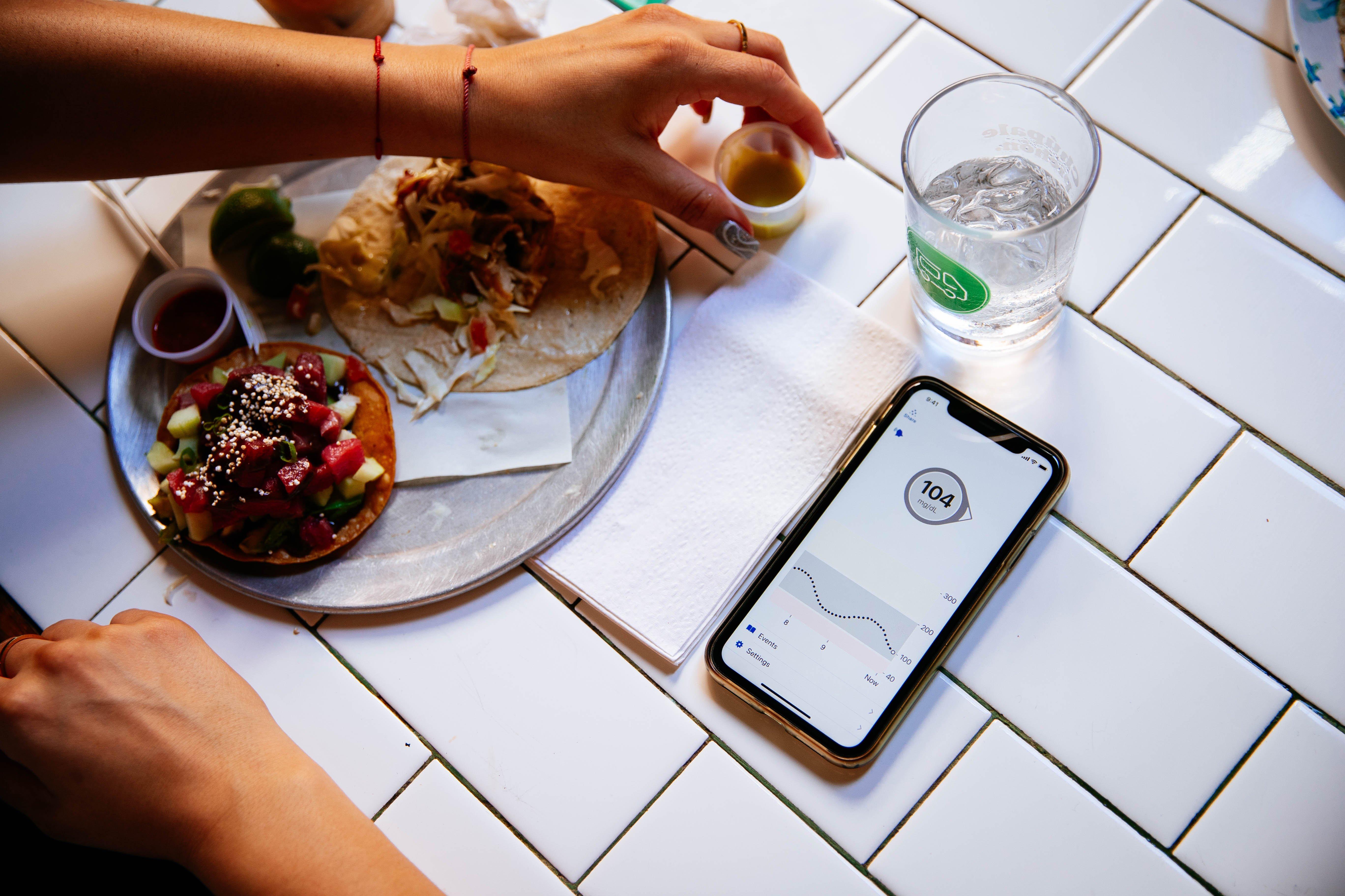 phone displaying glucose levels next to food