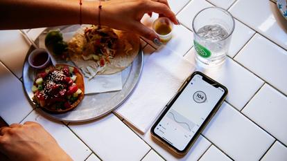 phone displaying glucose levels next to food