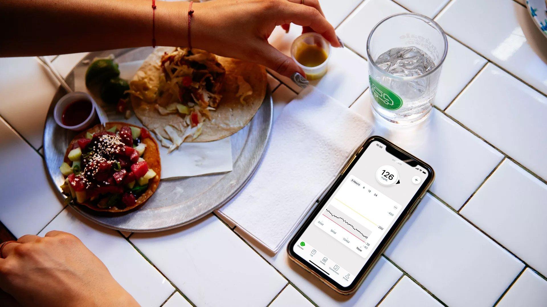 phone displaying glucose levels next to food