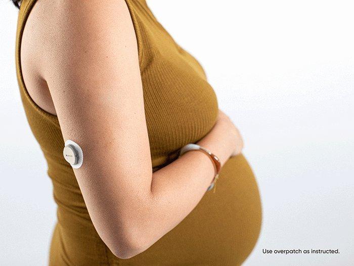 pregnant woman holding their stomach with dexcom product on