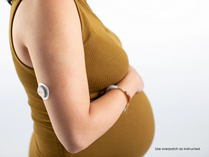 pregnant woman holding their stomach with dexcom product on