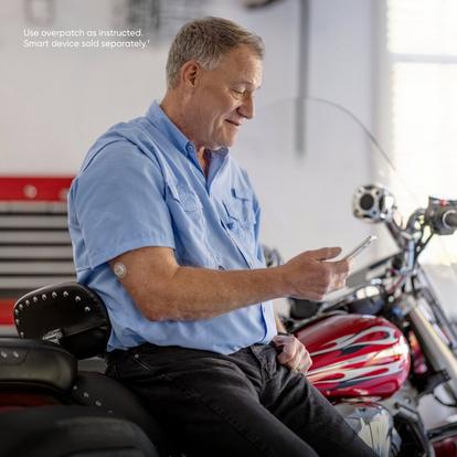 man leaning against motorcycle checking phone wearing g7 sensor