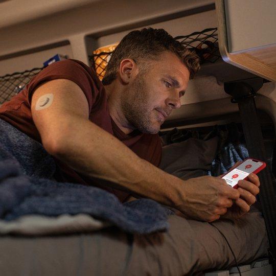 man checking phone in bed