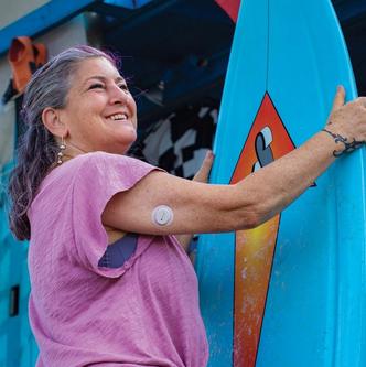woman holding surfboard smiling with sensor on arm