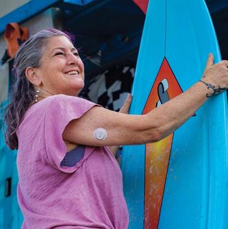 woman holding surfboard smiling with sensor on arm