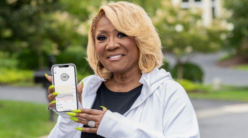 Headshot of Patti LaBelle holding smartphone with dexcom g6 app