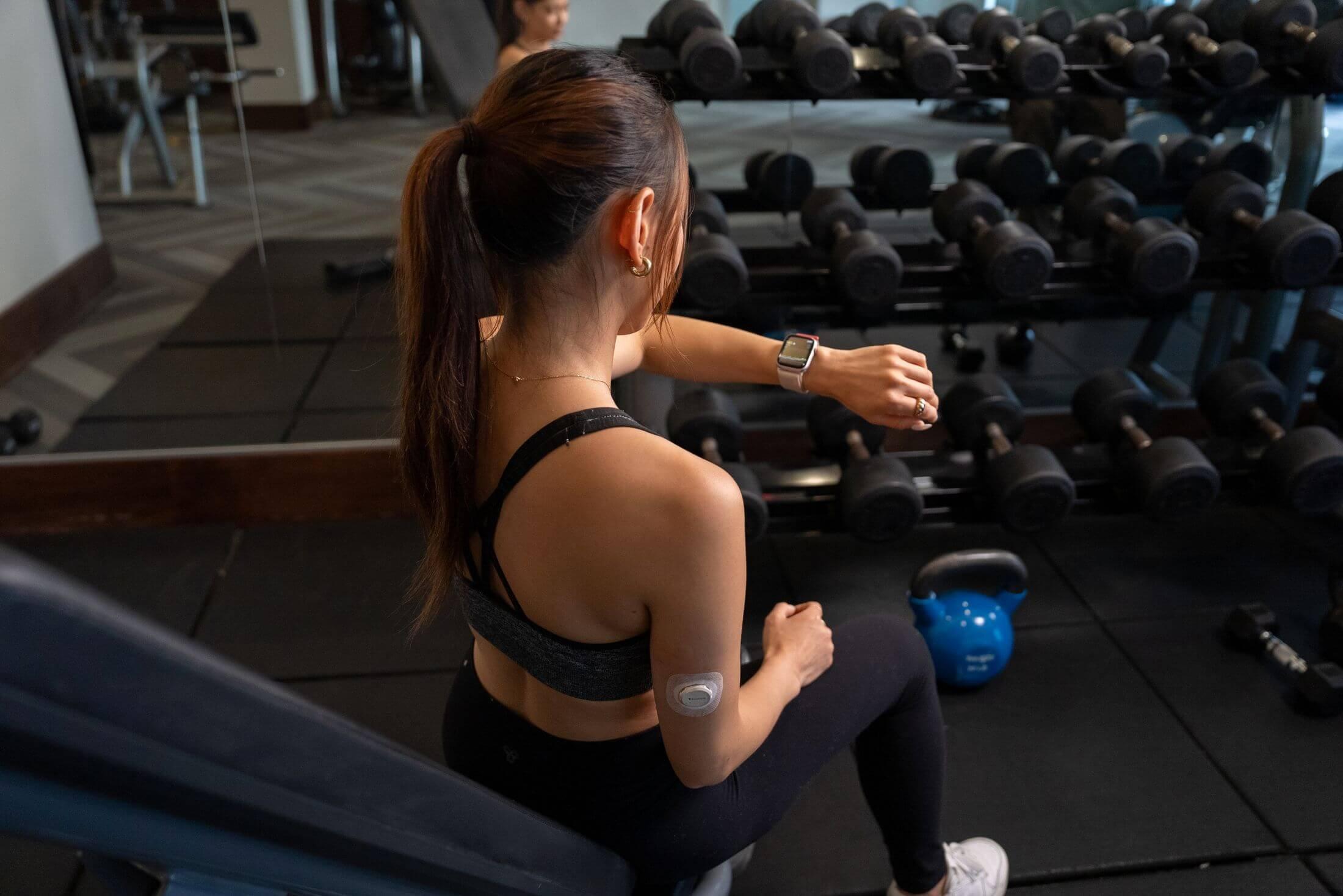 Amy checking her smart watch at the gym while wearing the Dexcom G7 CGM sesnor